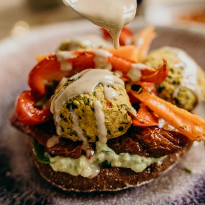 A delicious vegan falafel burger with fresh vegetables and tahini sauce, perfect for a healthy meal.