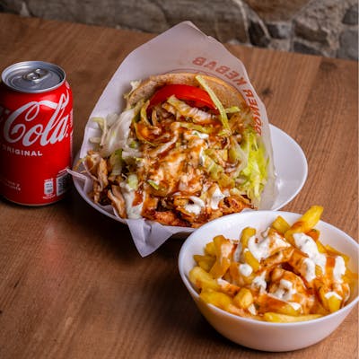A tempting doner kebab with fries and a refreshing cola on a wooden table.