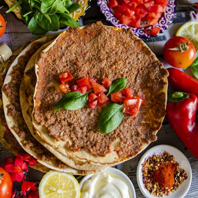 A top-down view of delicious homemade Turkish lahmacun garnished with fresh basil and vibrant ingredients.