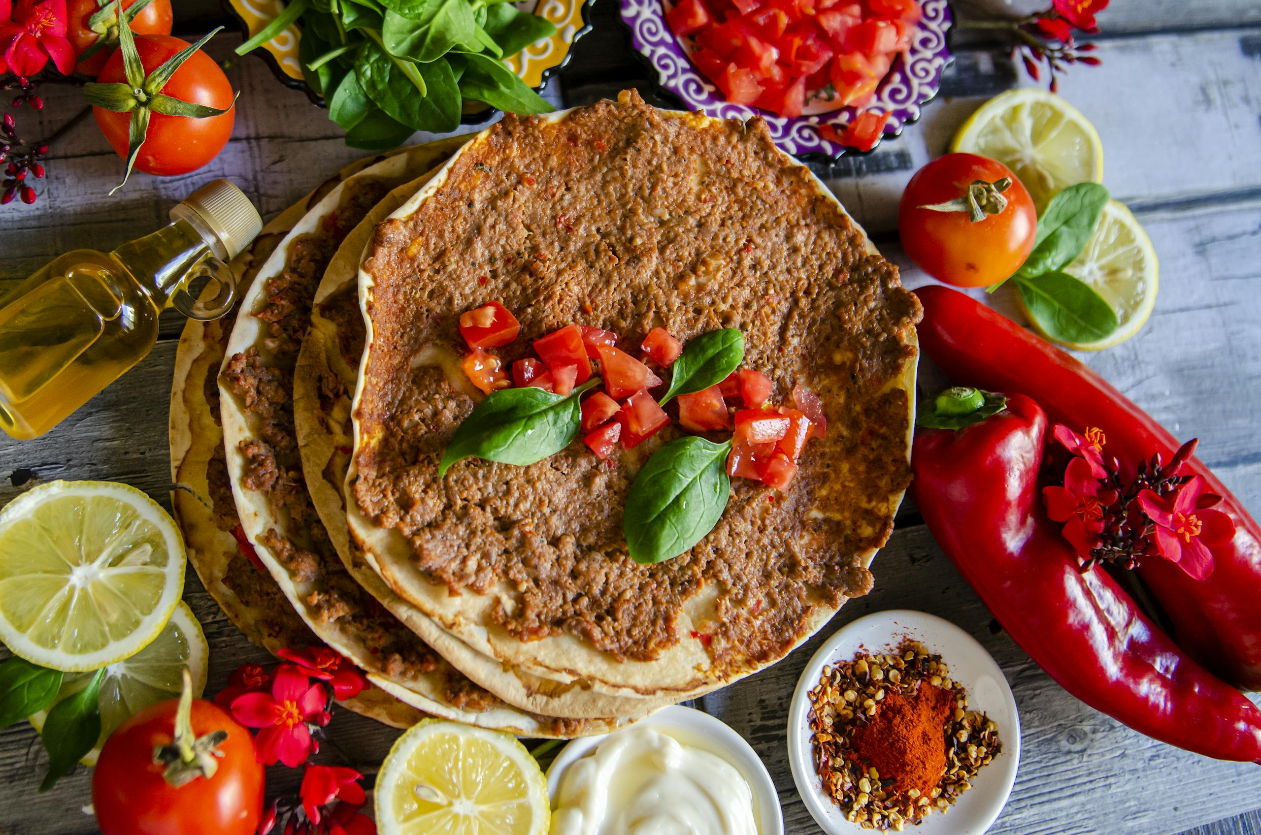 A top-down view of delicious homemade Turkish lahmacun garnished with fresh basil and vibrant ingredients.