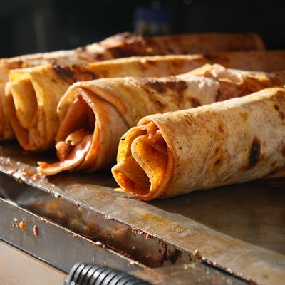 Close-up of traditional Turkish Dürüm wraps being grilled, showcasing delicious street food.