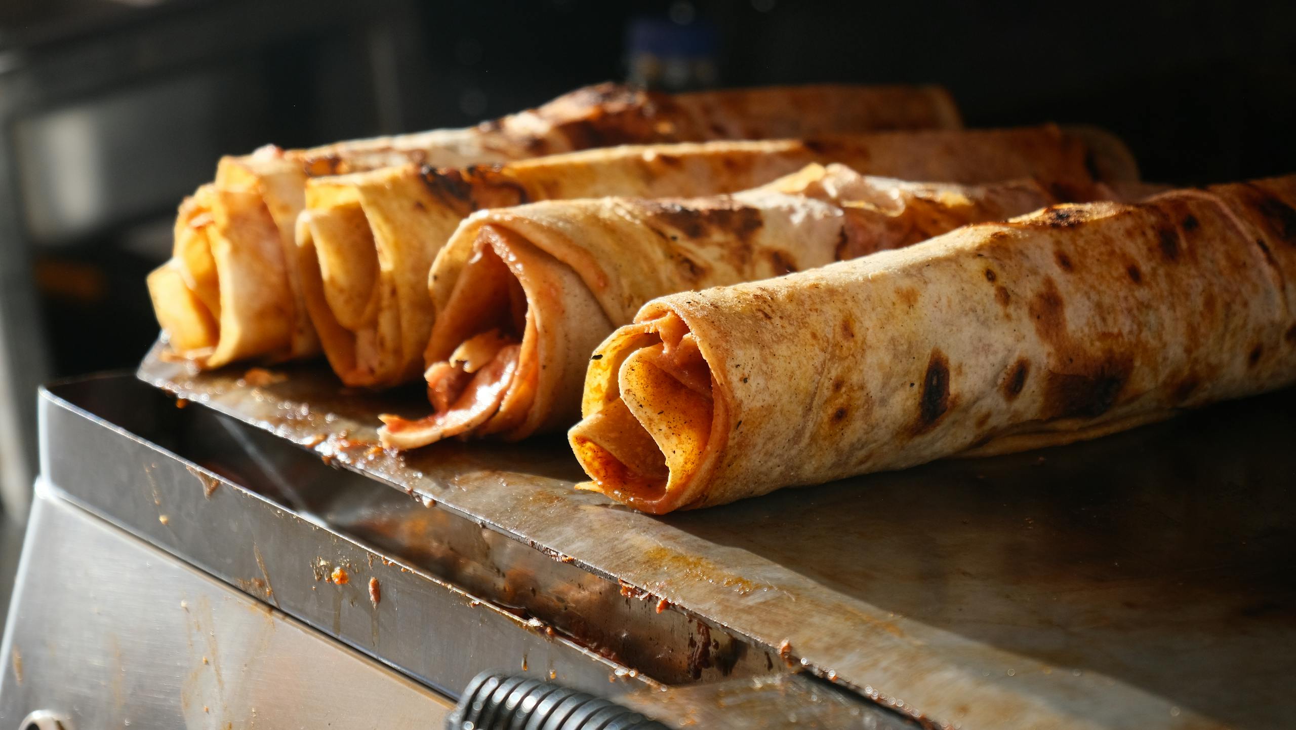 Close-up of traditional Turkish Dürüm wraps being grilled, showcasing delicious street food.