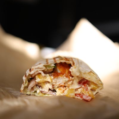 Delicious close-up of a fresh doner kebab with vegetables inside a wrap, perfect for food photography.