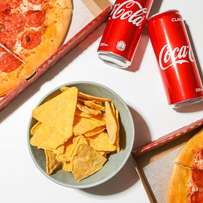 Delicious pepperoni pizza, cola cans, and chips on a white background. Perfect for a snack spread.