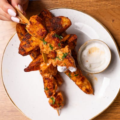 Top view of chicken skewers with dipping sauce on a plate, ready to serve.
