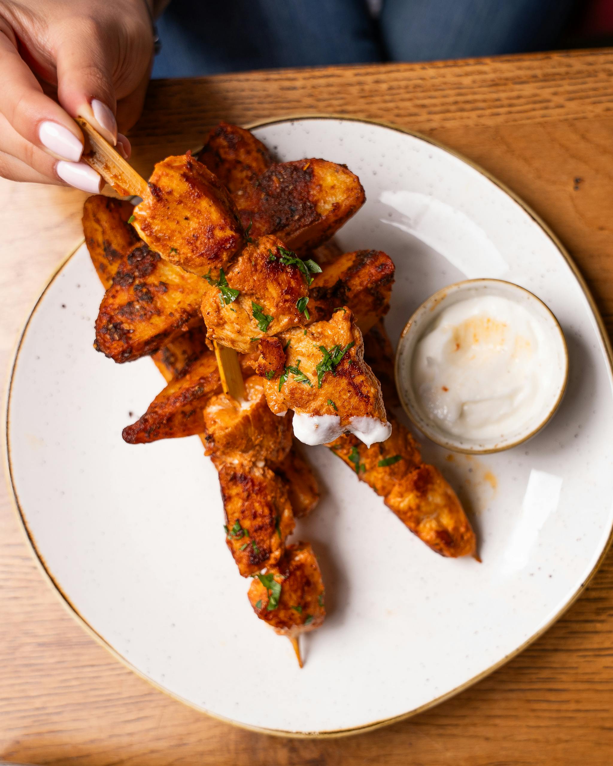 Top view of chicken skewers with dipping sauce on a plate, ready to serve.